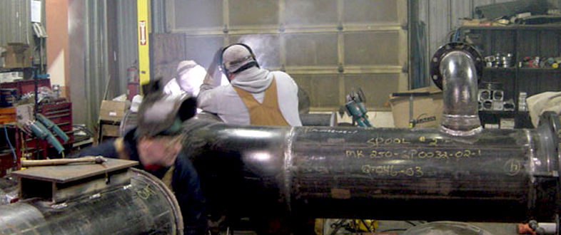 Fabricators working on a steel pipe assembly