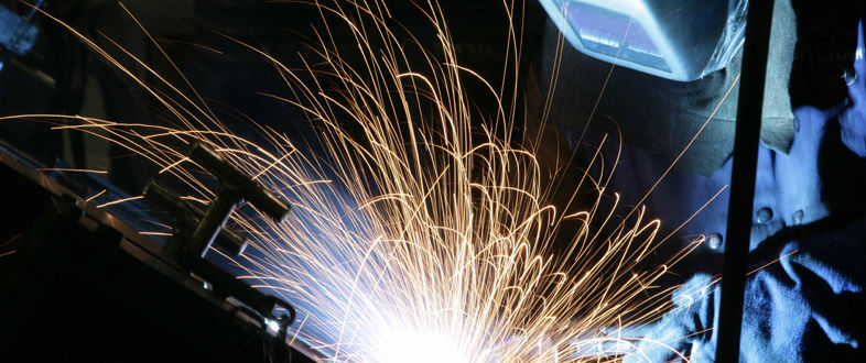 Welder repairing a steel part with sparks flying